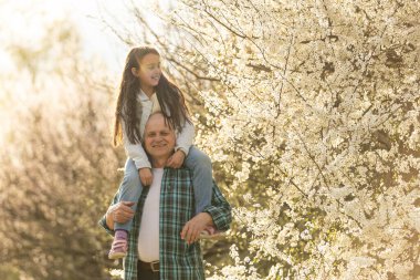 Gülümseyen çocuk doğada mutlu büyükbabasına sarılıyor..