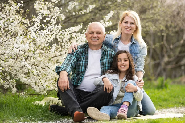 Három generációs család ül kívül tavasszal természet — Stock Fotó