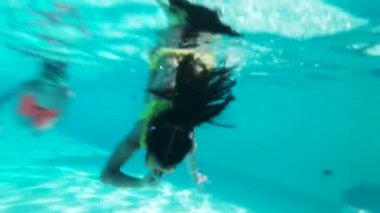 Gözlüklü mutlu kız havuzda suyun altında yüzer. Kapat..