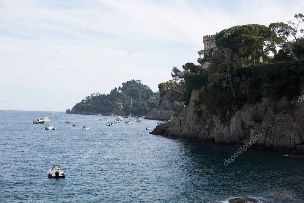 Fishing boats moored on water in harbor of Ligurian and Mediterranean Sea near coastline of Riviera di Levante of National park Cinque Terre Coast with blue sky, Riomaggiore village, Liguria, Italy.