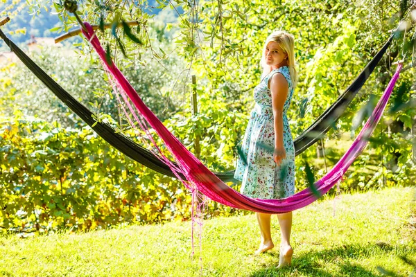 Hamakta oturan genç bir kadın yeşil çimlerin üzerinde