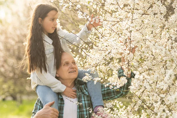 Lächelndes Kind umarmt seinen glücklichen Opa - draußen in der Natur. — Stockfoto