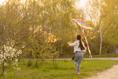 Mutlu çocuk dışarıda renkli uçurtmayla oynuyor. Yeşil bahar tarlasında eğlenen bir çocuk. Özgürlük ve hayal gücü kavramı