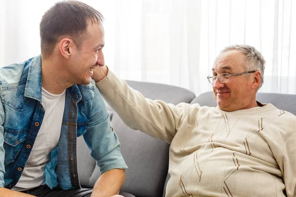 Glad pensionerad man och vuxen son pratar hemma — Stockfoto