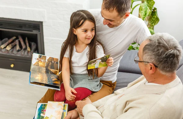 Famille souriante avec des grands-parents tenant un album photo à la maison — Photo