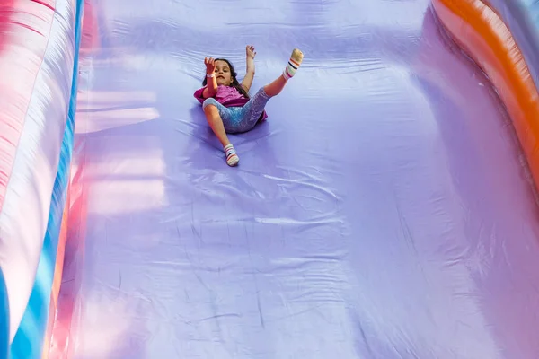 Šťastná holčička má spoustu zábavy na skákacím hradě během klouzání. — Stock fotografie