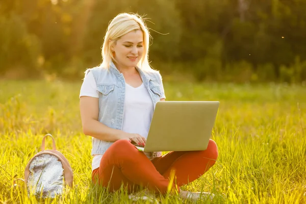 Femme euphorique à la recherche d'un emploi avec un ordinateur portable dans un parc urbain en été. — Photo