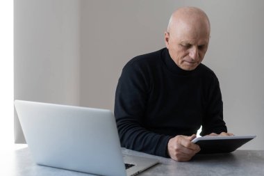 Kafkasyalı yaşlı işadamı, çalışma masasında oturan işadamının, grafik çizelgesi raporunu okuduktan sonra baş ağrısı çekmesi ve çalışma masasındaki kontrat belgelerini imzalaması sinirlerini bozdu.