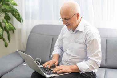 Bütçe Planlama. Son sınıf öğrencisi dizüstü bilgisayar kullanıyor ve not defterine yazıyor. Evdeki boş masada oturuyor..