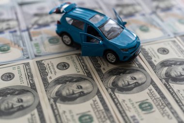 100 dolarlık banknotlarda küçük oyuncak araba, beyaz arka planda izole edilmiş yol olarak.