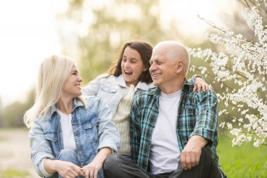grandfather with granddaughter and daughter in spring, senior man in the yard