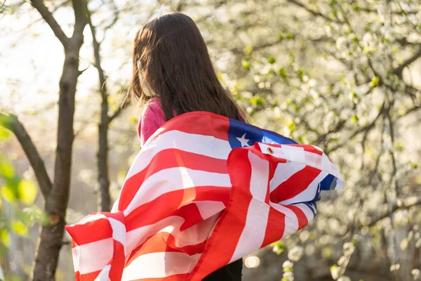 미소짓고 미국 국기를 흔들며 행복해 하는 귀여운 소녀. 국경일. 행복 한 꼬마 미국 국기를 든 귀여운 꼬마 소녀. 미국은 7 월 4 일 을 축하 한다. 독립일의 개념. — 스톡 사진