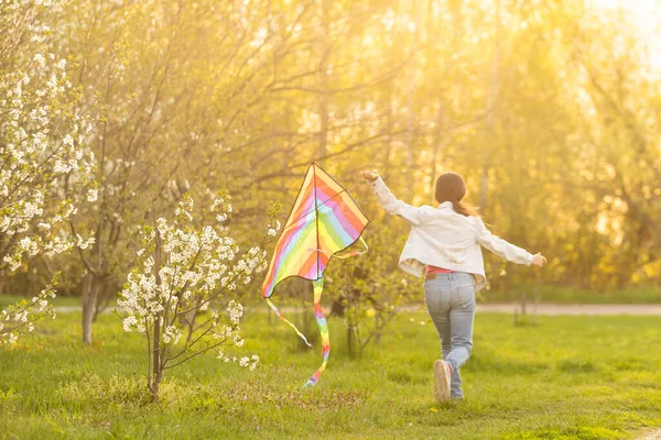 Happy little girl running with kite in hands on the beautiful field at sunrishe time — ストック写真