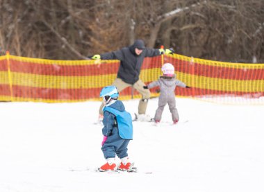 Küçük çocuk hocasıyla kayak yapmayı öğreniyor.