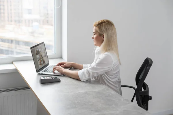 젊은 여성이 사무실에서 노트북 컴퓨터를 사용하여 실내에 앉아 행복하고 아름다운 사업을 하고 있는 모습 — 스톡 사진