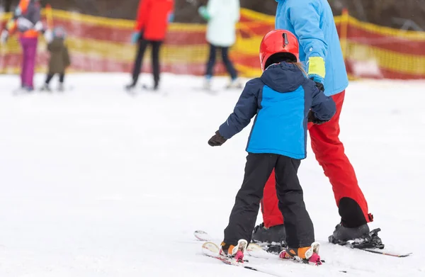 Eğitmen ve küçük çocuk kayak yapıyor. Kasklı, yeni yürümeye başlayan bir çocuk. Küçük çocuklar için kayak dersi. Kış sporu. Küçük kayakçı. — Stok fotoğraf