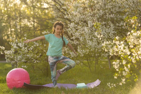 Little girl is doing fitness in the yard — стоковое фото