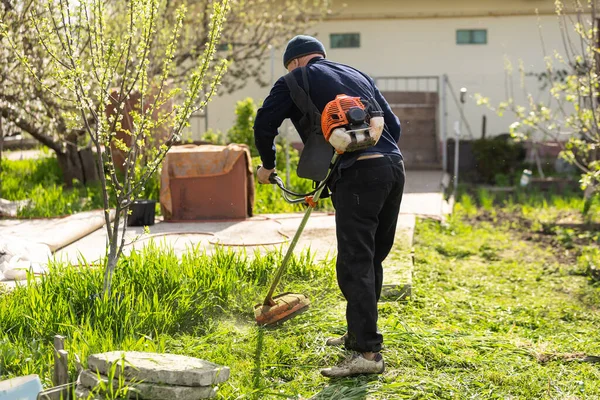 Αγρότης κουρεύει πράσινο γρασίδι με δρεπάνι στον αγρό — Φωτογραφία Αρχείου