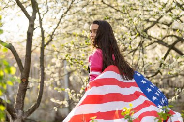 Gülümseyen ve Amerikan bayrağı sallayan sevimli küçük kız. Vatansever bayram. Mutlu çocuk, Amerikan bayrağı taşıyan şirin küçük kız çocuğu. ABD 4 Temmuz 'u kutluyor. Bağımsızlık Günü kavramı.