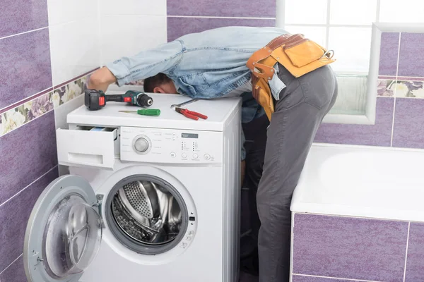 Homem repara uma máquina de lavar roupa — Fotografia de Stock