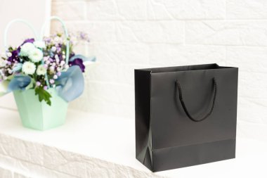 Beyaz arka planda buket ve siyah hediye çantası.