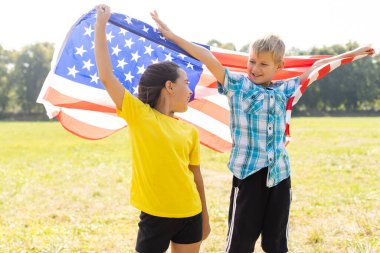 Çocuklar açık havada Amerikan bayrağıyla oturuyorlar..