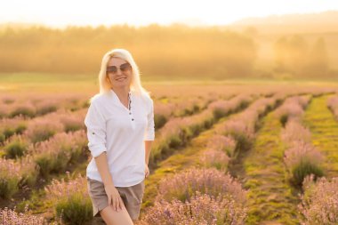 Lavanta tarlasında duran genç bir kadın ve arka planda gün doğumu.