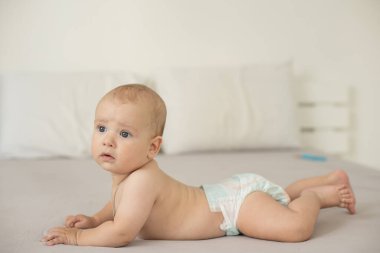 Beyaz güneşli yatak odasında sevimli bir erkek bebek. Yeni doğmuş çocuk yatakta dinleniyor. Küçük çocuklar için çocuk odası. Aile sabahı evde. Yeni doğan çocuk