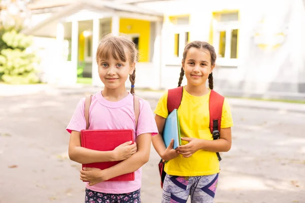 Retrato de duas meninas com bolsas de escola após a aula na escola — Fotografia de Stock