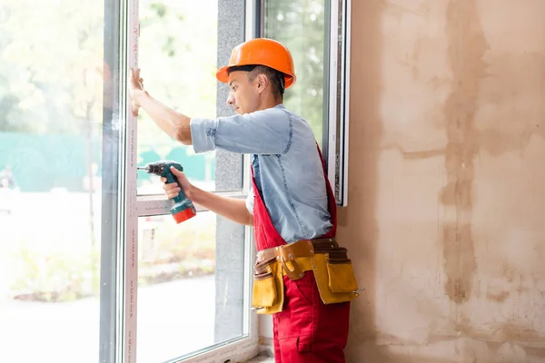 Manlig byggarbetare vid fönsterinstallation på byggarbetsplats — Stockfoto