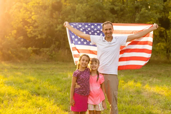 Happy family with the American flag in a wheat field at sunset. Independence Day, 4th of July. — Stock Photo, Image