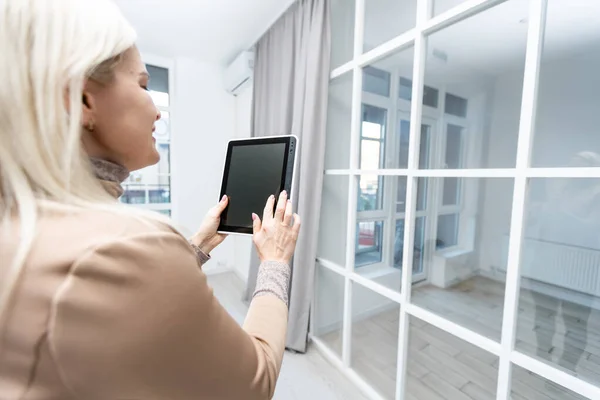 Hogar inteligente: mujer Controlando persianas con su tableta — Foto de Stock