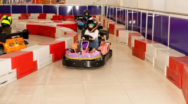 Bir go-kart karting yolda kapalı bir kask içinde gülümseyen küçük kız — Stok fotoğraf