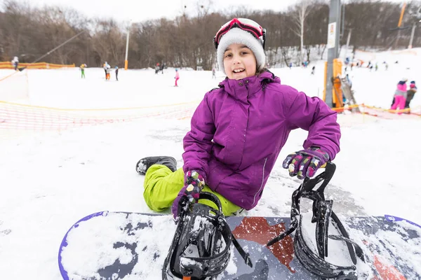 Liten söt flicka lära sig att rida en barnens snowboard, vintersport för barnet, säkerhet för aktiva sporter. — Stockfoto