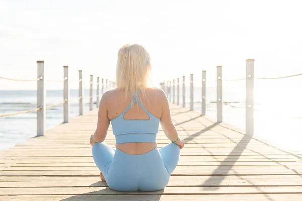 Donna che fa esercizi di yoga in riva al mare. — Foto Stock
