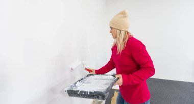 Daireye taşınırken duvarları patenlerle boyayan kadın. Yeni evin yenilenmesi ve iyileştirme konsepti