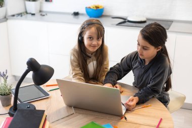 İki çocuk öğrenci birlikte video oyunu oynayarak öğretmenle çevrimiçi çalışıyor. Kardeşler Covid 19 salgınından dolayı karantina sırasında bilgisayarla evde eğitim görüyorlar..