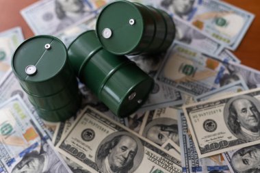 Dolar banknotlarının üzerinde duran üç varil petrol. Petrol işi, satış, üretim, takas, ticaret geliri.