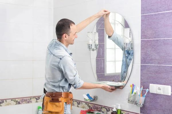 Handyman installing a mirror in bathroom — Stockfoto
