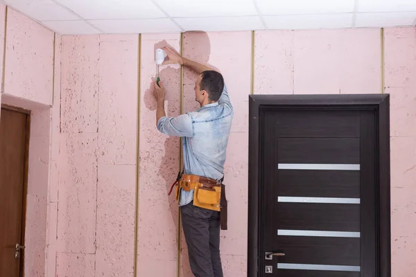 壁にセキュリティ アラームをインストールする若手電気技術者. — ストック写真