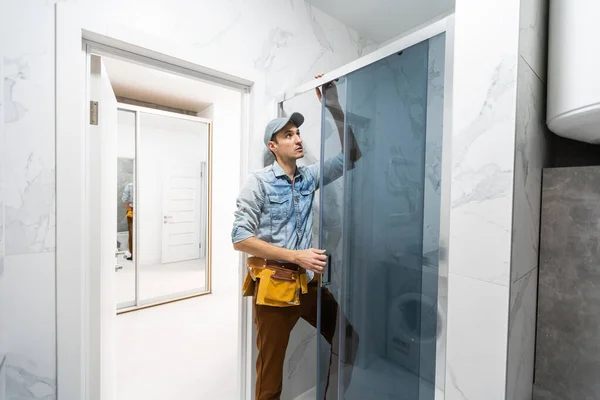 현대식 샤워실 의 욕실 치수를 재고 있는 제복을 입은 수리공. — 스톡 사진