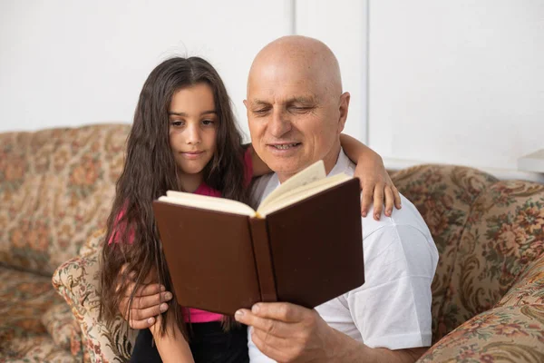 Happy little girl with grandfather reading story book at home — Stock Photo, Image