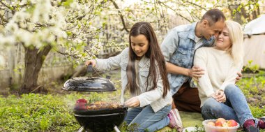Bahçelerinde barbekü yapan bir aile.