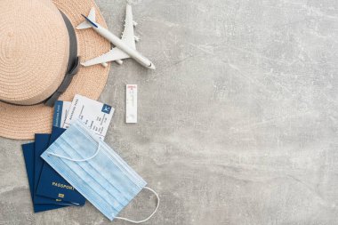 Seyahat ve tatil konsepti. Aksesuarlar ve eşyalar. Uçak biletleri ve yüz maskeleriyle pasaport yerine uçak oyuncağı. Üst görünüm düzlüğü kopyalama alanı ile yatıyordu.