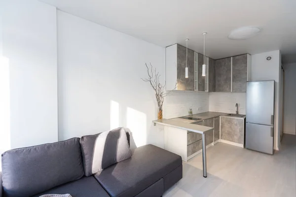 Design intérieur moderne de luxe confortable d'un studio dans des couleurs blanc supplémentaire avec des meubles à la mode dans un style minimaliste. sol carrelé blanc, cuisine, espace détente et lieu de travail — Photo