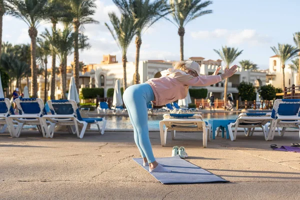 Atleta in forma donna che fa esercizi di stretching all'aperto giardino tropicale villa piscina, mattina presto Hotel resort vacanza, assistenza sanitaria, benessere — Foto Stock