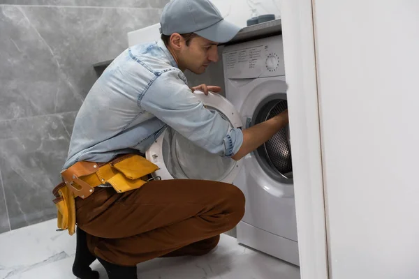 Слесарь-сантехник ремонтирует стиральную машину — стоковое фото