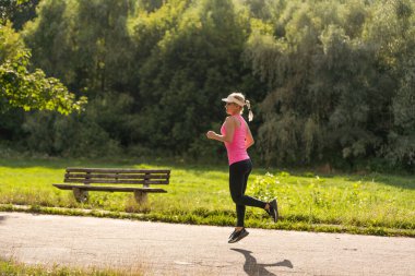 Genç fitness kadın atlet yolda koşuyor.