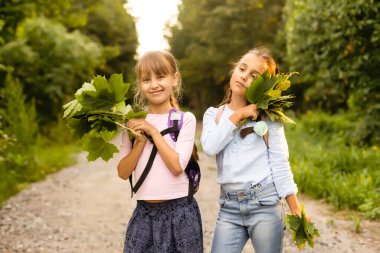 Sonbahar günü sırt çantalı mutlu okul çocukları, doğada kamp yaparken eğlenen heyecanlı çocuklar.