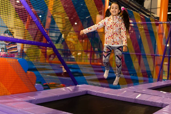 Portrét malé roztomilé dítě dívka hrát a skákání na trampolíně v dětské herně, vnitřní hřiště. Aktivní dívka se baví ve sportovním centru. — Stock fotografie